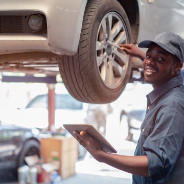 Mechanic fixing a car while checking warranty